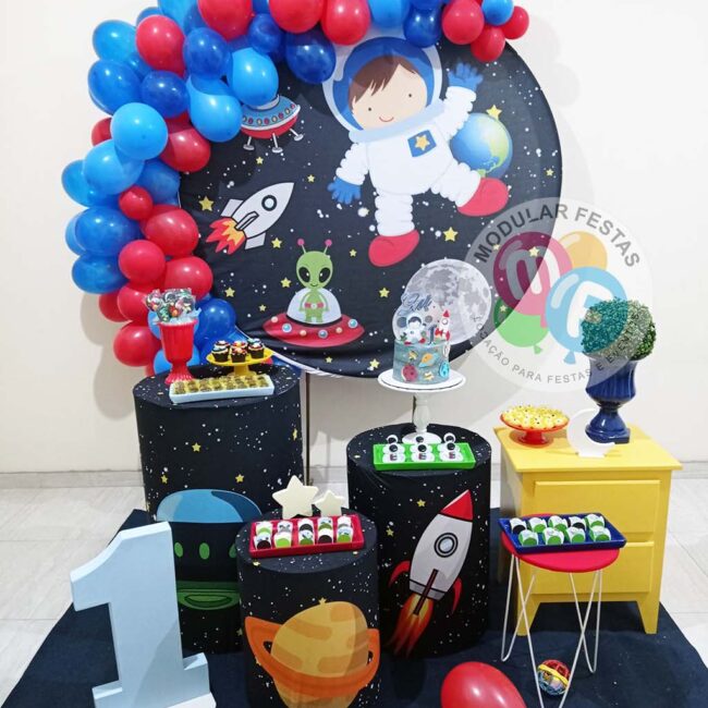 Kit Pegue e Monte infantil e juvenil festa de aniversário temática Pequeno Astronauta Sonhe alto preto, azul e vermelho com trio cilindros de MDF e painel de aro redondo com capas personalizadas, cômoda amarela, mesinha tripé e vários outros itens decorativos.